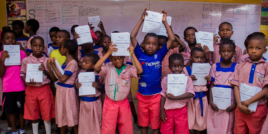 Community school children holding books by Volta Drive